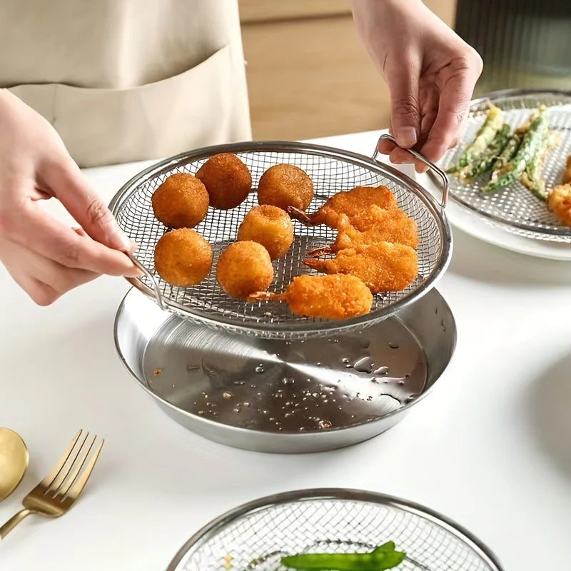 Person using a wire mesh strainer to remove fried food from a pan on a white surface.